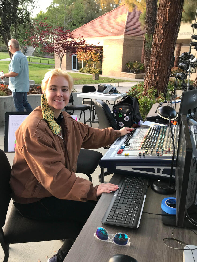 Hayden stationed at a sound board for an outdoor theatre production.